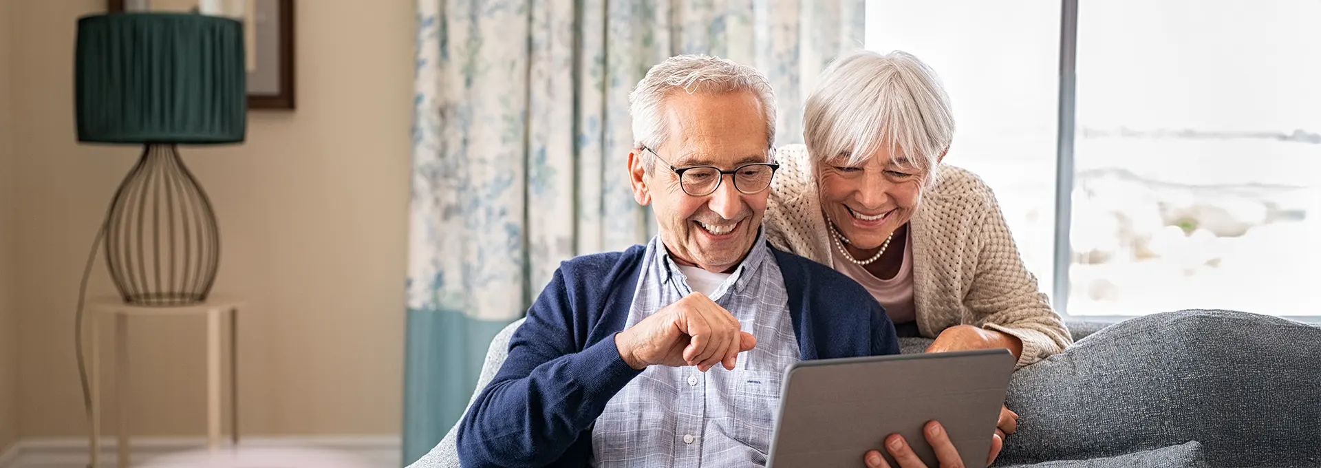 Renterpaar schaut freudig auf ein Tablet